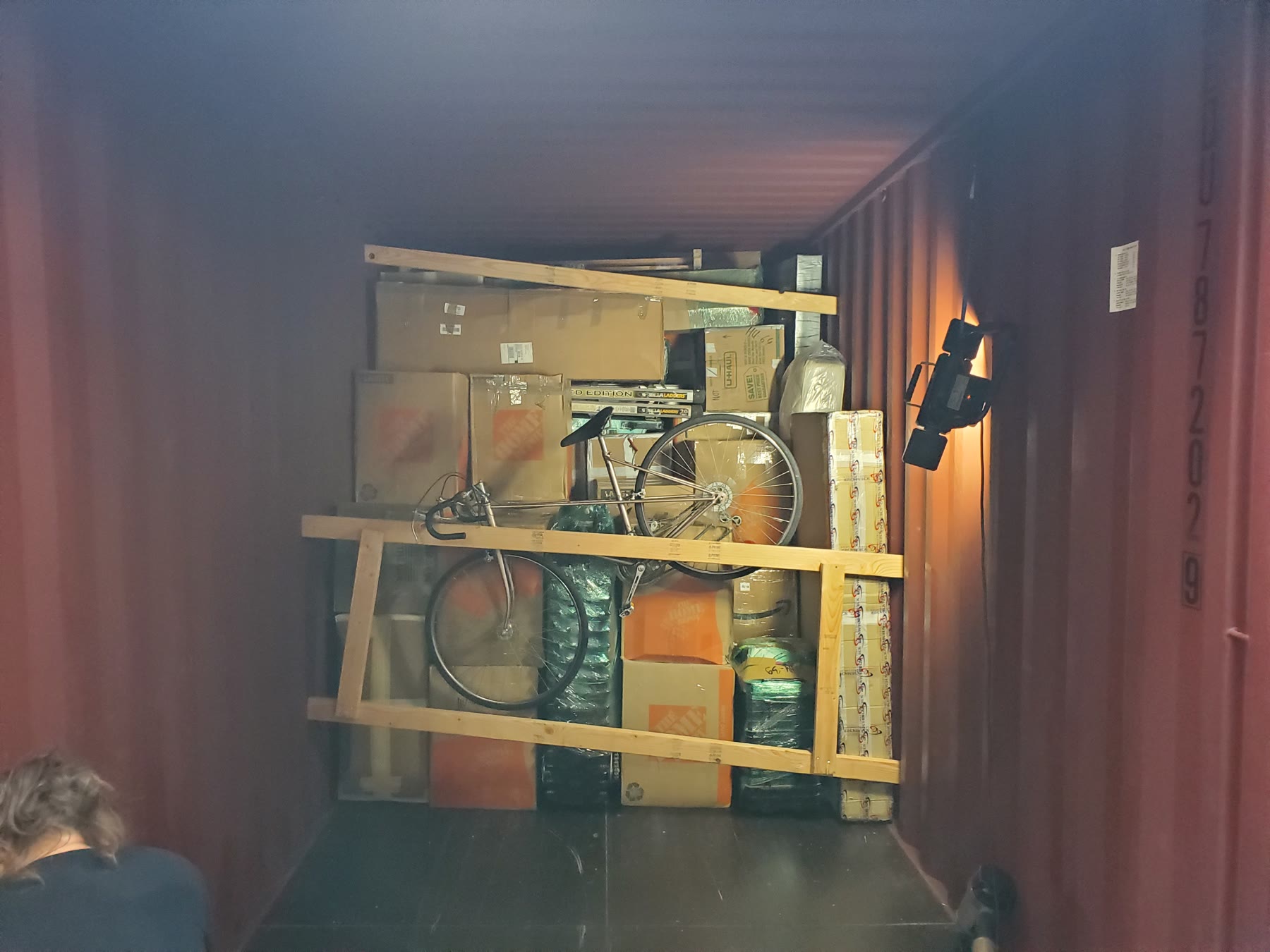 Bicycle and boxed household cargo secured inside a shipping container