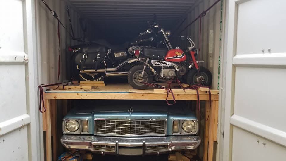 Classic Mercedes loaded beneath two motorcycles on a custom wooden rack inside a container