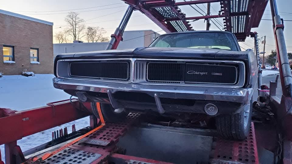 Classic Dodge Charger with an incomplete front end on a vehicle carrier