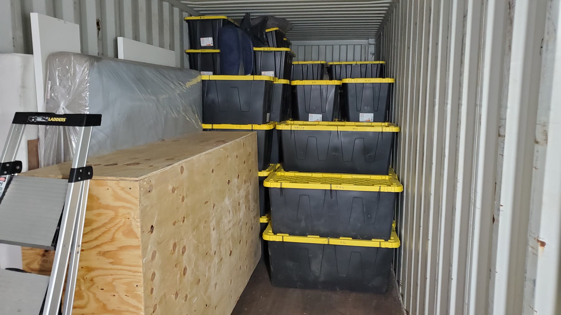 Organized storage totes and a wooden crate inside a shipping container