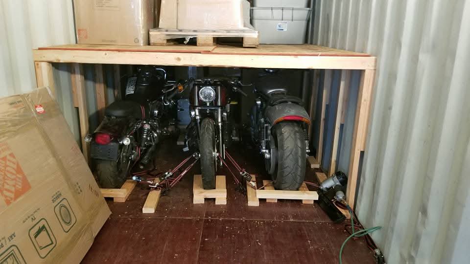 Three motorcycles secured with a timber support structure inside a shipping container