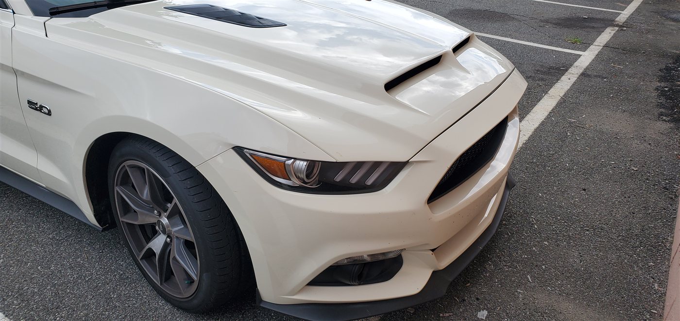 White Ford Mustang 5.0 front quarter panel detail with headlights and hood vents