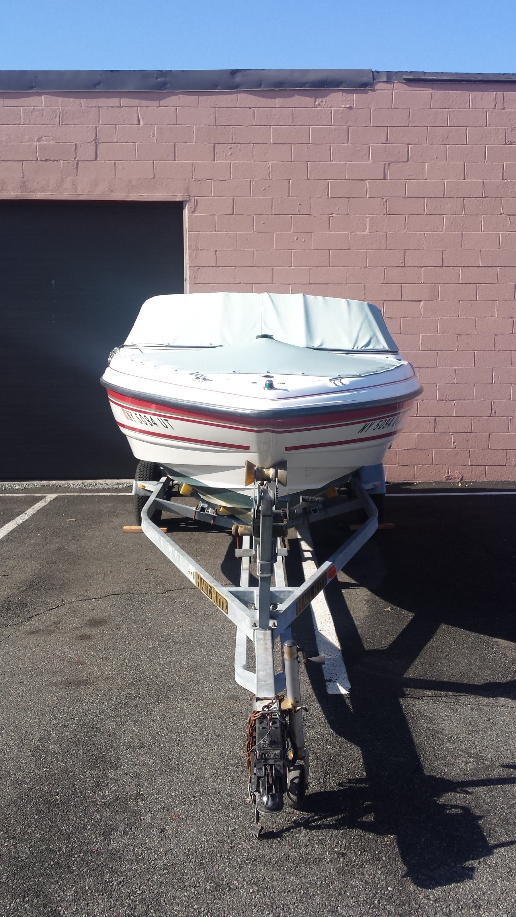 Covered recreational speedboat secured on its road trailer for transport
